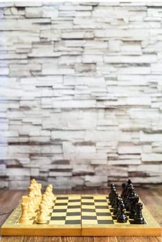 Chess pieces on chess board on wooden table. Blurred background with copy space