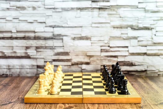 Chess pieces on chess board on wooden table. Blurred background with copy space