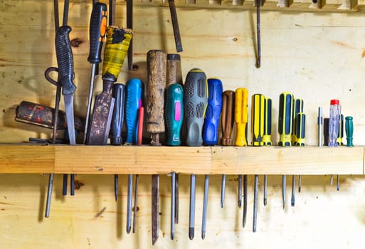 Phillips and flat screwdrivers hanging on wooden wall
