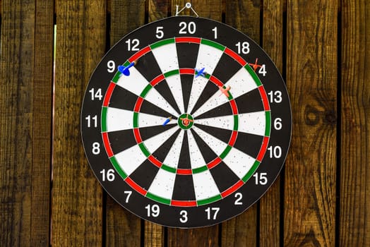 darts hanging on a wooden wall with a dart stuck in the center