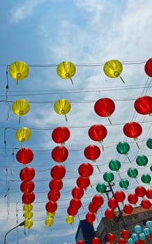 Vibrant red and yellow lanterns suspended across open balconies under a serene blue sky, representing festive celebrations of chinese new year and traditional cultural decor. good for background