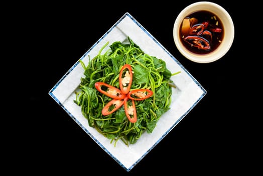 Vietnamese fried sweet potato leaves with garlic on black background