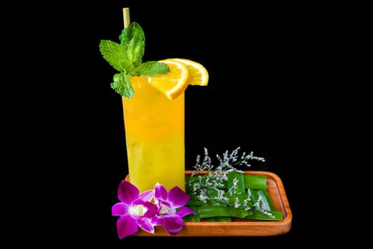 Orange juice with slice of orange, with flowers isolated on black background