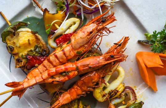 Grilled shrimps with fish on skewers on isolated on black background top view