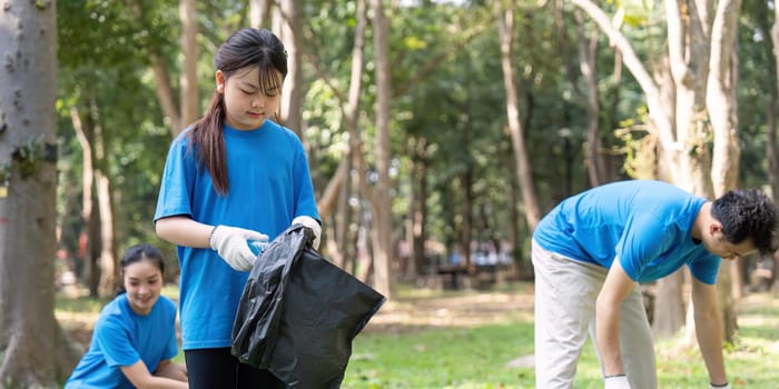 A diverse family participates in a park cleanup, showcasing teamwork and dedication to environmental conservation.