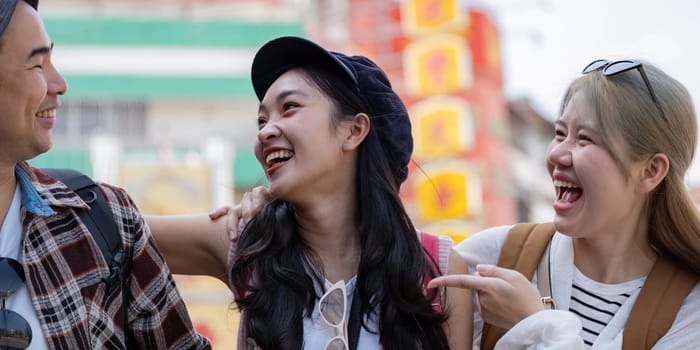 A close up of young Asian friends laughing together in a lively market, showcasing the happiness and connection that comes with travel and friendship.