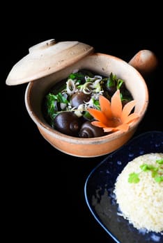 Boiled snails stuffed with pork in a pot with vegetables on black background sideview