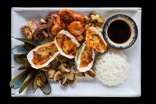 Sauteed seafood on white plate close up isolated on black background top view