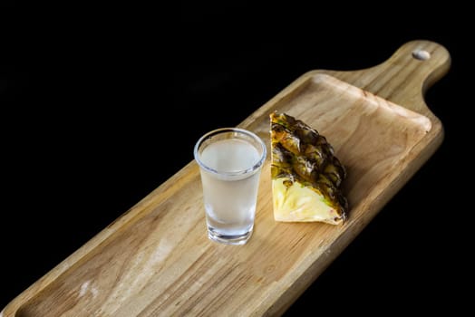 Alcohol shot made of pineapple juice on wooden board with copy space