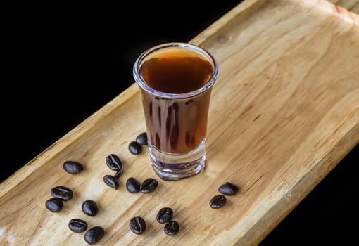 Alcohol shot made of coffee on wooden board with coffee beans with copy space