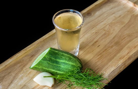 Alcohol shot made of cucumber, garlic and dill on wooden board with copy space