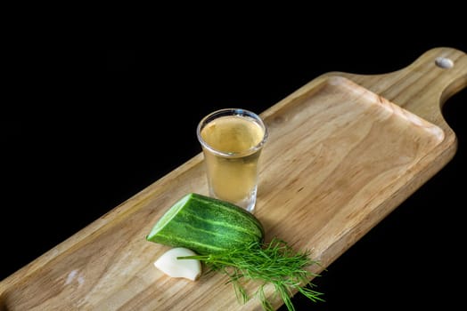 Alcohol shot made of cucumber, garlic and dill on wooden board with copy space