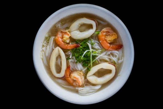 Traditional vietnamese soup Pho with seafood on black background