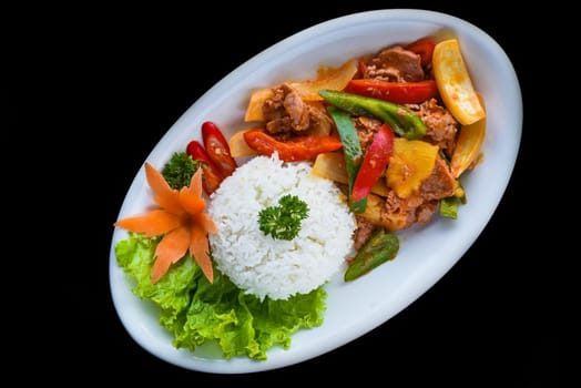 Stewed pork with vegetables and rice isolated on black background top view