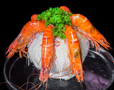 Five orange shrimps inside of coconut with sauce isolated on black background top view