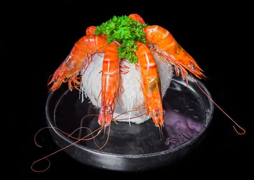 Five orange shrimps inside of coconut with sauce isolated on black background top view