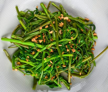 thai fried spinach on a white plate top view