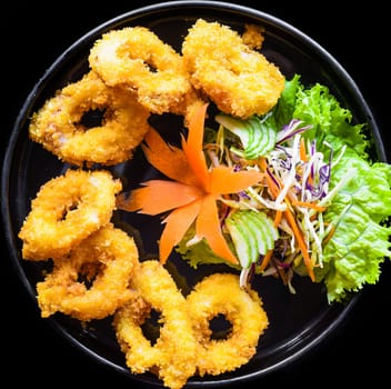 Fried squid or calamari in batter on a black plate close up top view