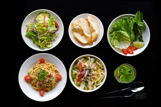 Lunch set made of chicken soup, salad, banh mi,pasta carbonara, lemonade on black background