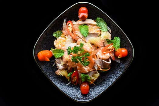 Salad made of shrimps and grapefruit isolated on black background top view