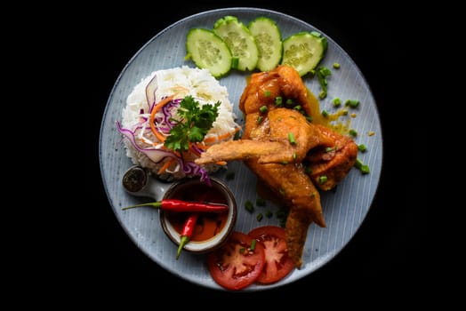 Roasted chicken wing in Vietnamese style with rice, vegetables and sauce isolated on black background top view