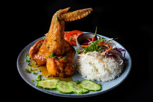 Roasted chicken wing in Vietnamese style with rice, vegetables and sauce isolated on black background top view