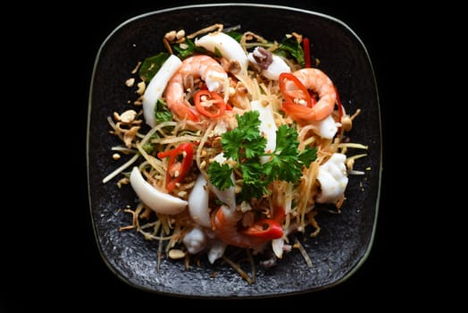 Salad made of shrimps and squid isolated on black background top view
