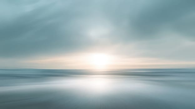 A beautiful blue ocean with a sun setting in the background. The sky is cloudy and the sun is just beginning to set