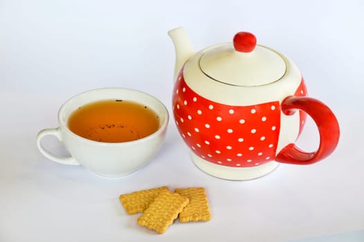 Cup of tea next to a dotted teapot and three cookies isolated on white background