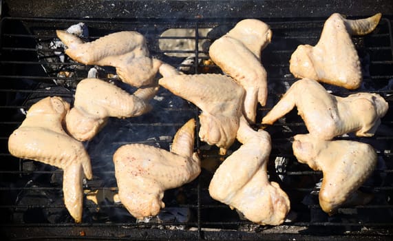 Raw chicken wings marinated in sour cream and spices, grilling on the grill grate. Start cooking, barbecue