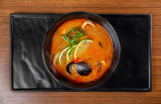 Soup tom yum with seashells and mussels top view on wooden table