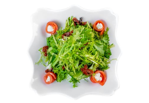Fresh salad with arugula, salmon, cream cheese and sun-dried tomatoes on white background
