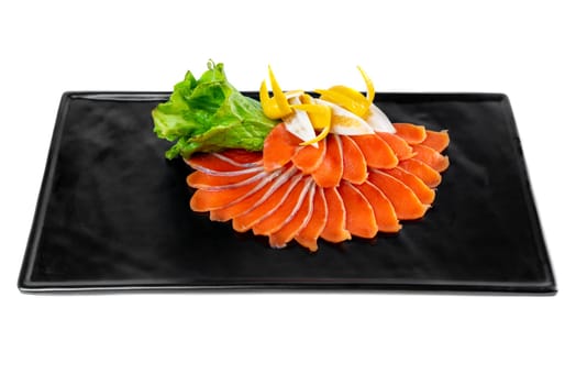 slicing appetizer of red fish slices on a black plate on a white background top view
