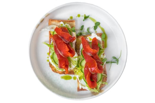 toasts with smoked salmon,crean cheese and vegetables on a white plate close up