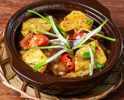 Vietnamese braised dishes with pork meat and pineapple with vegetables on wooden table