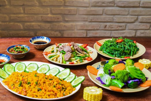 Vietnamese braised beef with papaya, fried rice with pork, salad and sauces on wooden table