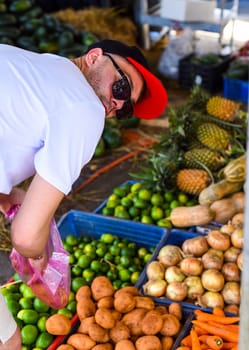 Young man choosing vegetables on the Vietnamese market Vinh Hai Nha Trang