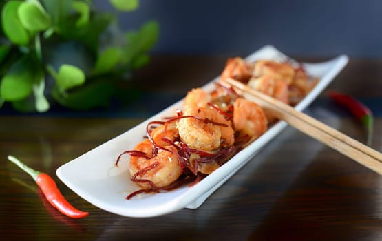 Grilled shrimp with onions and chili on a white plate on the table. For asian food menu