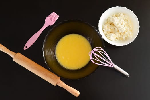 Making curd biscuits. melted butter and sugar in a bowl next to curd and kitchen utensils.