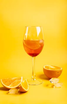 Cocktail Aperol spritz with oranges and ice on bright yellow background