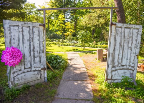 Creative idea for garden decoration: opened old white painted wooden doors with cute artificial flower