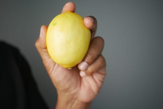 A person holds a ripe lemon close to the camera.