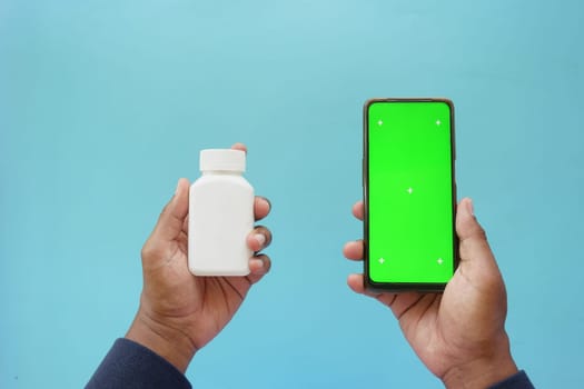 Person with white pill bottle and green phone.