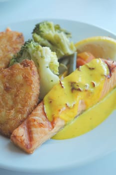Tasty salmon fillet with hollandaise sauce and sides.