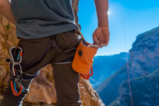 Male hand with magnesia powder close-up, against the background of beautiful mountains, the hand of climber who prepares for training outdoors, a man climbs in Twin Caves, Greece on a sunny day.