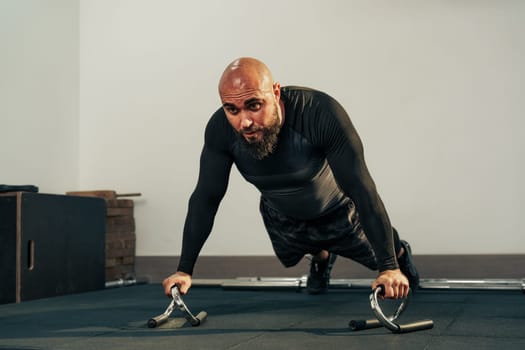 A dedicated fitness enthusiast is executing push-ups with handles in a well-equipped gym. The focus on strength training showcases commitment to physical fitness and health.