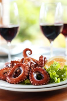 Fried octopus on a plate and a glass of wine. selective focus. Generative AI, food