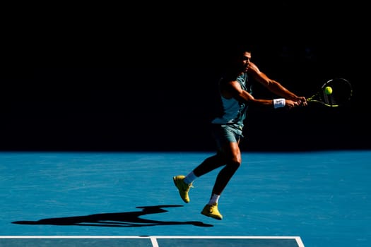 MELBOURNE, AUSTRALIA - JANUARY 19: Carlos Alcaraz of Spain hits a backhand to Jack Draper of Great Britain on day eight of the 2025 Australian Open at Melbourne Park on January 19, 2025 in Melbourne, Australia.