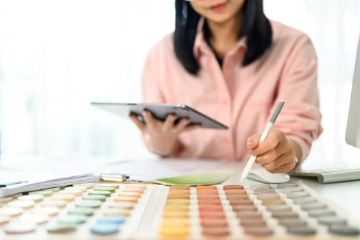 Interior designer holding digital tablet selecting color tones for a project.