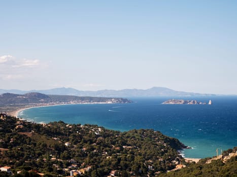 beautiful seascape with a bay with big beach and small island in the distance, the sky is clear and weather is calm, concept of peaceful and serene landscape, copyspace for text